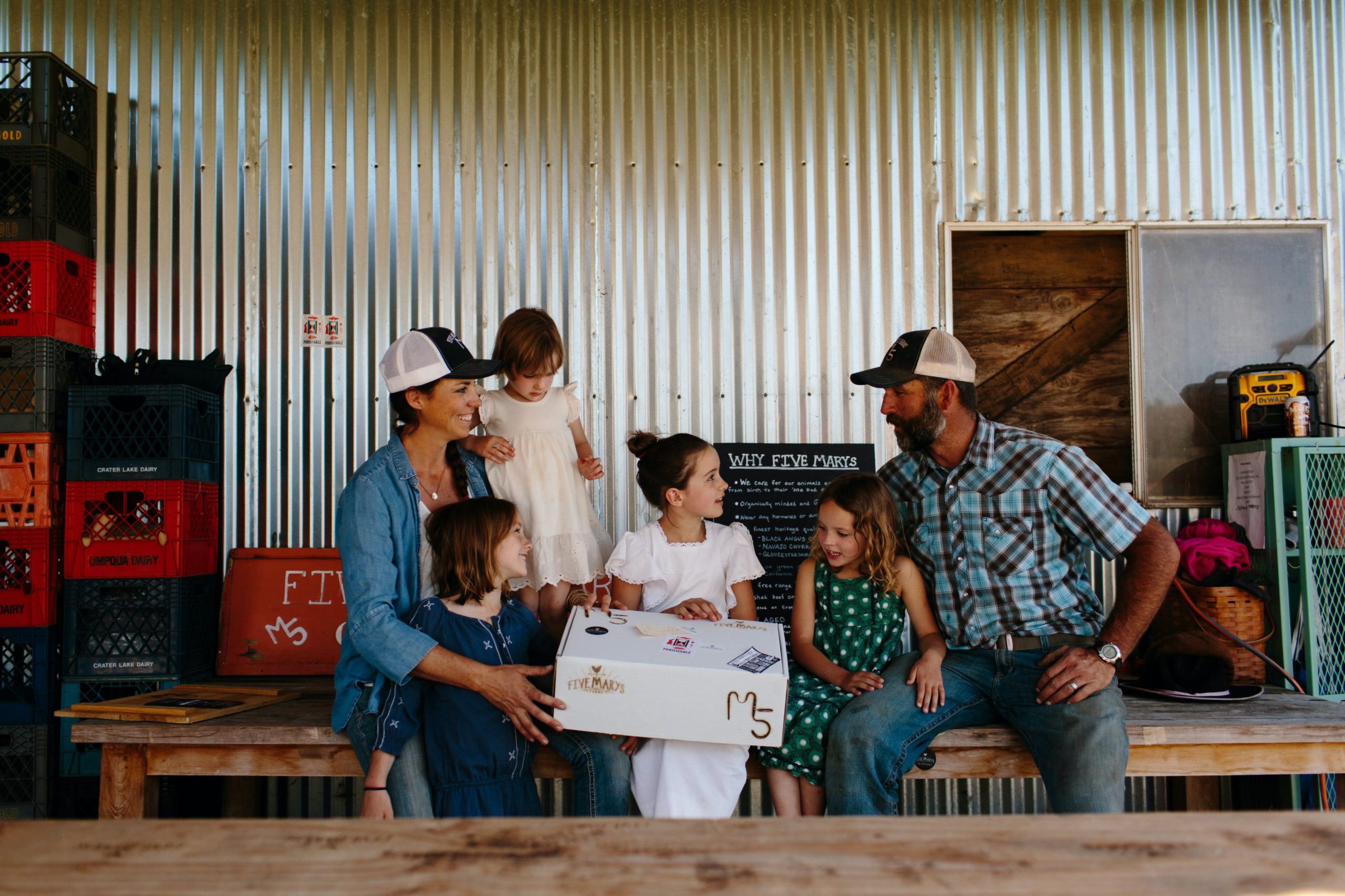 Mary and Brian Heffernan and their four daughters with a Five Marys Farms meat box in the barn